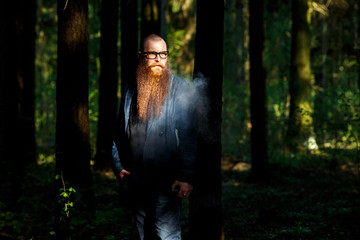 Vape bearded man. An adult white short-haired man with a very long beard in glasses smokes an...