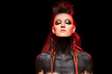 Portrait of a young savage girl. Naked shoulders and neck are covered with black paint. Conceptual...