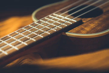 Ukulele closeup. Orange and dark background.