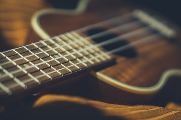 Fototapeta premium Ukulele closeup. Orange and dark background.