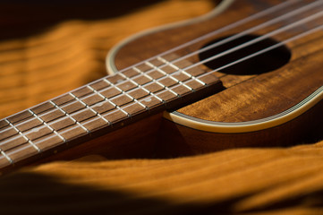 Fototapeta premium Ukulele closeup. Orange and dark background.
