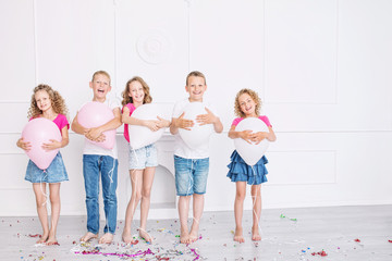 Happy beautiful cute kids smile at the holiday party with balloons and confetti together in the white room