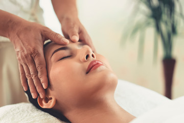 Obraz na płótnie Canvas Hands of the masseuse make manual massage of the head to a beautiful client Asian woman in spa salon at hotel or resort. Beauty lifestyle,people or scalp treatment and hair growth stimulation concept