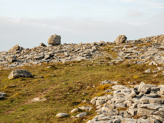 Terrain in Burren national park, County Clare, Ireland, Stones and small patch of grass. cloudy sky.
