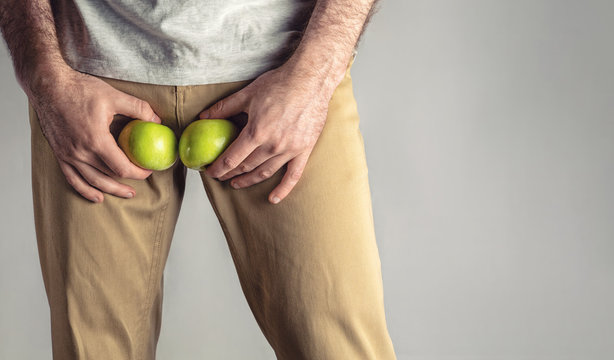 A man at the level of the genitals , holding a ripe and rotten apple. Disease for men. The concept of protection of sexually transmitted infections. Copy space