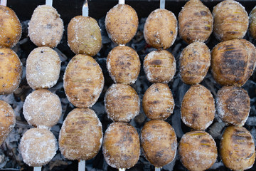 baked potatoes on the coals on the grill with a Golden crust. food preparation