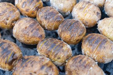 baked potatoes on the coals on the grill with a Golden crust. food preparation