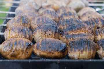 baked potatoes on the coals on the grill with a Golden crust. food preparation