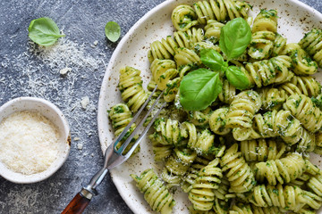 Pasta with pesto and parmesan on a concrete background. View from above.