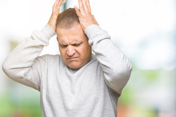 Middle age arab man wearing sport sweatshirt over isolated background suffering from headache desperate and stressed because pain and migraine. Hands on head.