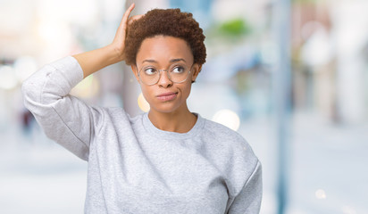 Young beautiful african american woman wearing glasses over isolated background confuse and wonder about question. Uncertain with doubt, thinking with hand on head. Pensive concept.