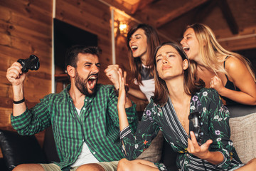 Happy friends playing video games at home