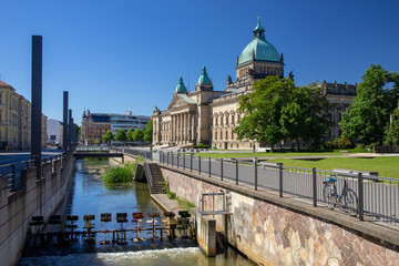 Fototapeta na wymiar Panorama of the Federal Administrative Court Leipzig - Germany with River in the foreground at blue sky.At the courthouse is the text Federal Administrative Court in German