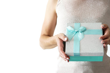Woman in sparkly shirt holds gift box with ribbon in hands