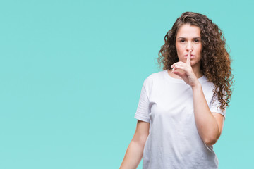 Beautiful brunette curly hair young girl wearing casual t-shirt over isolated background asking to be quiet with finger on lips. Silence and secret concept.