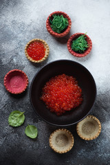 Vegetable tartlets with red caviar and seaweed salad, flatlay on a grey stone background, studio shot