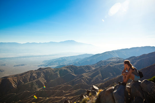 A woman looks out over the Coachella Valley from the Keys View Lookout in Joshua Tree National Park, California. Haze blows through Banning Pass from the Los Angeles metropolitan area. The San Andreas faultline can be seen rising midway across the valley floor near Palm Springs.