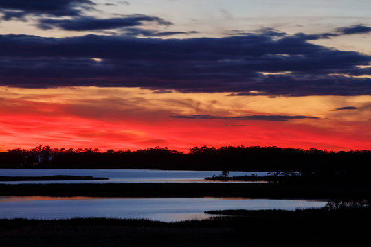 A scarlet sunset over Buzzard Bay in Roanoke Sound as seen from Run Hill, a series of large sand dunes that form the northern border of the Nags Head Woods Preserve on the Outer Banks of North Carolina.