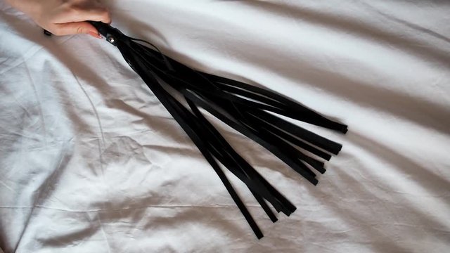 leather whip Flogger in hand of dominatrix girl for sex