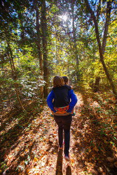 Mother and son, TNC Conservation Coordinator Kate Murray givers her son Eli a piggyback ride along the popular Sweetgum Swamp loop trail at the Nags Head Woods Preserve.