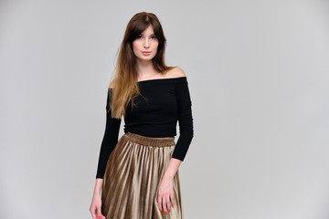 Photo portrait of a beautiful pretty brunette girl in a black sweater on a gray background. A woman is satisfied with her life, she stands in front of the camera, smiling and talking. Made in studio.