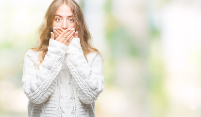 Beautiful young blonde woman wearing winter sweater over isolated background shocked covering mouth with hands for mistake. Secret concept.