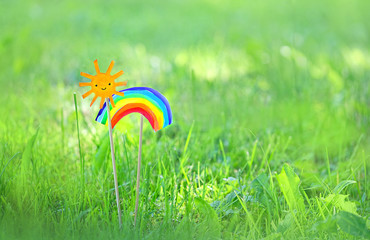 cute kawaii paper sun and rainbow on abstract green grass background. children's creativity, good...