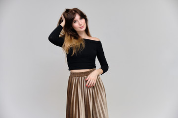 Fototapeta premium Photo portrait of a beautiful pretty brunette girl in a black sweater on a gray background. A woman is satisfied with her life, she stands in front of the camera, smiling and talking. Made in studio.