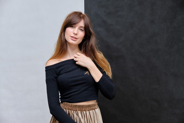 Beauty portrait of a beautiful pretty brunette girl in a black sweater on a two-color background. A woman is happy with life, stands in front of the camera, smiles. Made in a studio.