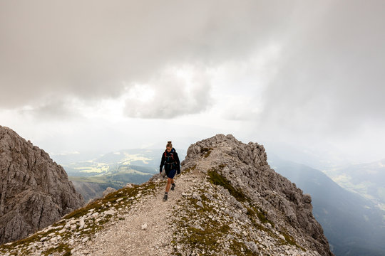 Vajolet-Tower-Hike (from Vigo di Fassa), Trentino, Italy: A female hiker on a cliff below the Rosengartenspitze with a view down into the valley.