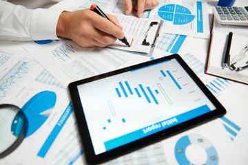 Businessman working and calculating, reads and writes reports. Using tablet pc. Office employee, table closeup. Business financial accounting concept.