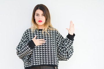 Young woman wearing casual sweater over isolated background Swearing with hand on chest and open...