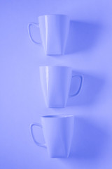 3 blue coffee mugs on blue background in a vertical row with empty copyspace
