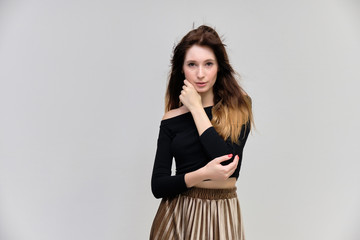 Fototapeta premium Photo portrait of a beautiful pretty brunette girl in a black sweater on a gray background. A woman is satisfied with her life, she stands in front of the camera, smiling and talking. Made in studio.