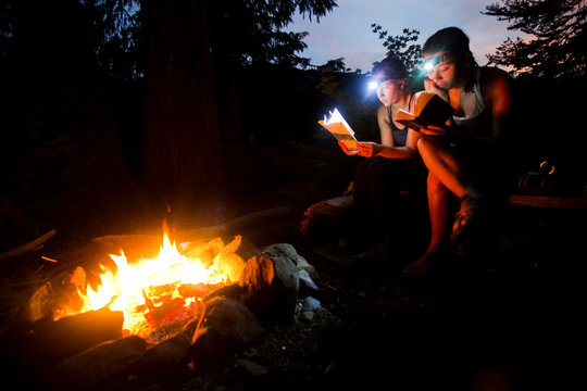 Two women read by firelight in the Alpine Lakes Wilderness in the North Cascades.      