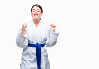 Young beautiful woman wearing karate kimono uniform over isolated background excited for success with arms raised celebrating victory smiling. Winner concept. © Krakenimages.com