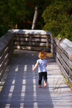 A child running on the ADA Trail during a group playdate with Outer Banks homeschoolers in the Nags Head Woods Preserve.