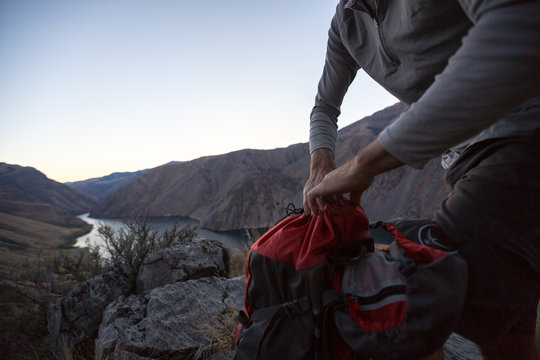 A man packs up his backpack overlooking the Snake River in Hells Canyon, Idaho.