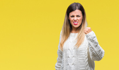 Young beautiful woman casual white sweater over isolated background angry and mad raising fist frustrated and furious while shouting with anger. Rage and aggressive concept.