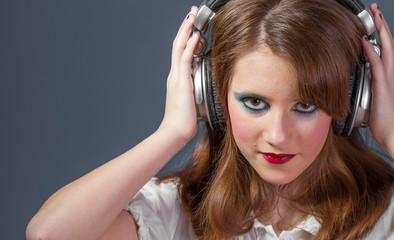 Fototapeta premium redhead girl with helmet on her head listening to music on a flat gray background