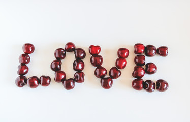 Love made of red sweet  cherries on the white background. Copy space. 