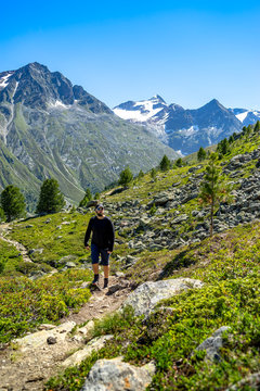 Hiker on a trail with the Stubai alps in the background