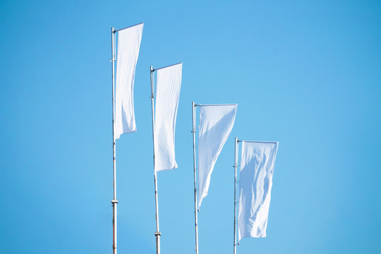 A lot of white flags against the blue sky hanging on the mast, copy space