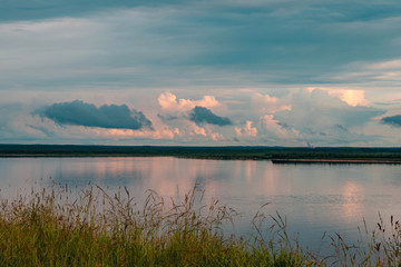 Dramatic beautiful pink blue orange sunset at river with reflection and clouds on natural background