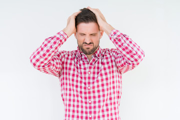 Young handsome man wearing shirt over isolated background suffering from headache desperate and stressed because pain and migraine. Hands on head.