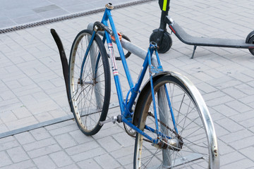 Broken old bike. The bent wheel. Attached to the rack