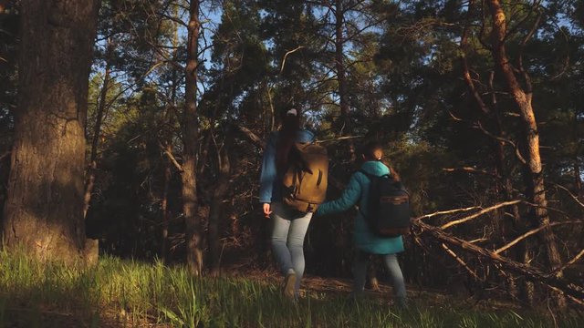 Happy family travels. mother and daughter travelers walking through the woods with a backpack. Hiker Girs in pine forest. The tourist enjoys life and nature. vacation adventure travel.
