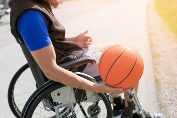 Disabled young basketball player on a wheelchair holding ball and beeing active in sport