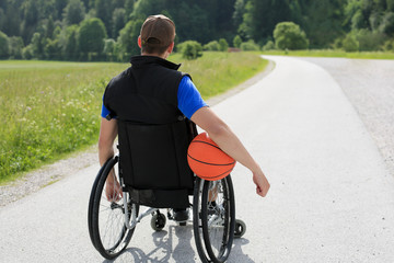 Disabled young basketball player on a wheelchair holding ball and beeing active in sport