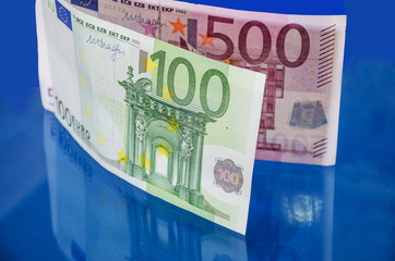 500 and 100 euro banknotes on a blue background reflecting